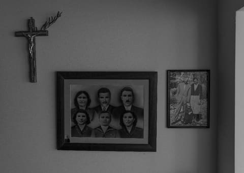 Family photographs and a crucifix on the wall of a village house
