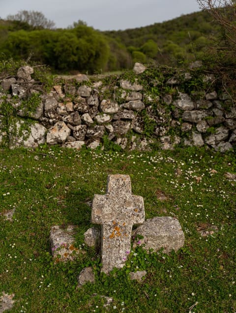 A stone cross beside a dry-stone wall, the cemetery near the necropolis